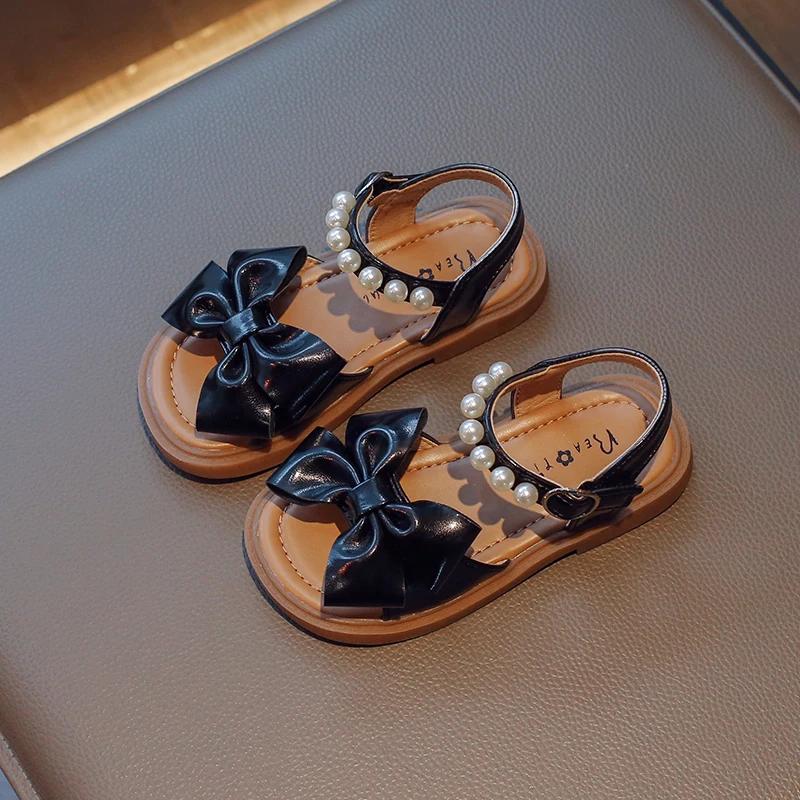Детская обувь Bow Pearls Open-toe 2024 Новые летние туфли на плоской подошве для детей Повседневные сандалии для девочек Нескользящие PU простые японские сандалии для платьев 22 чёрный Sole Style